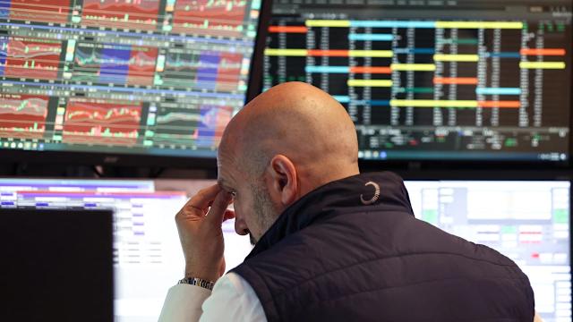 A person with a bald head is sitting in front of multiple screens displaying colorful financial data and charts, illustr