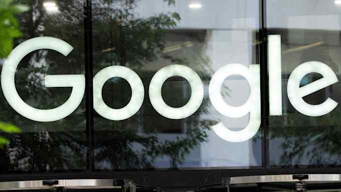 A large illuminated Google logo displayed on a glass exterior wall.