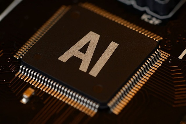 一枚標有「AI」的大型黑色電腦晶片,帶有金色接腳,安裝在電路板上,周圍環繞著精密的電子元件